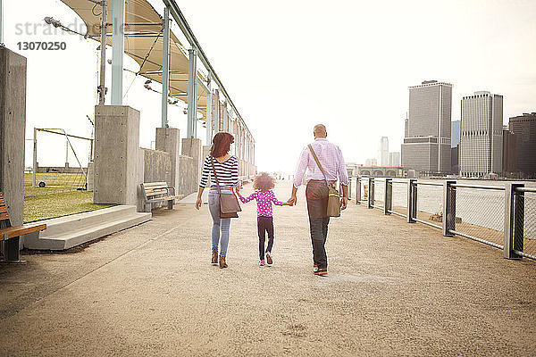 Rückansicht einer Familie  die auf einer Promenade in der Stadt bei klarem Himmel spazieren geht