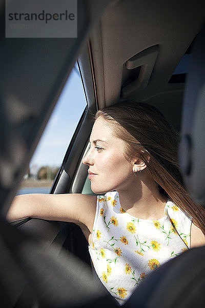 Frau  die auf Reisen durch ein Autofenster schaut
