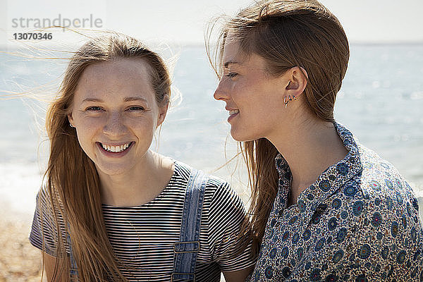 Porträt einer lächelnden Frau mit Freundin am Strand