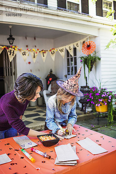 Mutter hilft der Tochter bei der Tischdekoration während der Halloween-Party