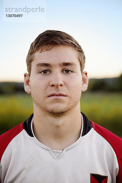 Selbstbewusster Rugby-Spieler steht auf dem Feld gegen den Himmel