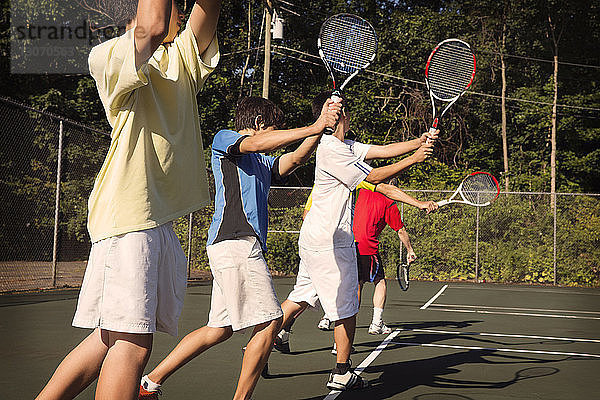 In der Reihe stehende Spieler spielen Tennis gegen den Zaun auf dem Platz