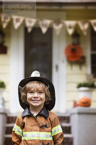 Porträt eines lächelnden Jungen im Halloween-Kostüm  der vor dem Haus steht