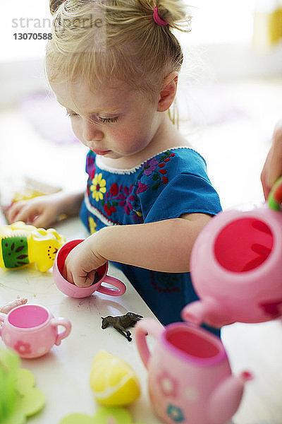 Kleines Mädchen spielt zu Hause mit Plastikspielzeug am Tisch