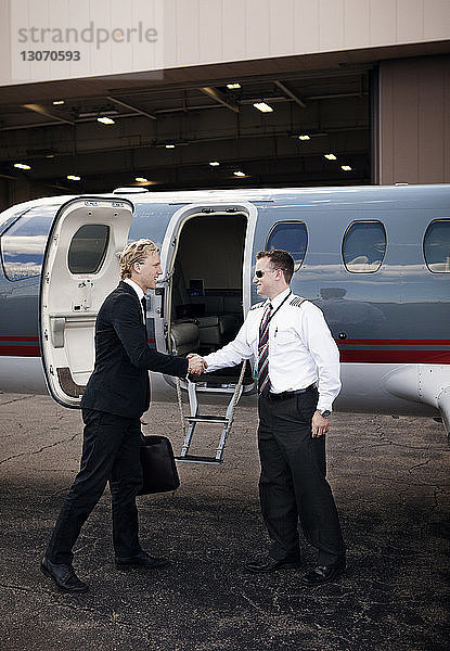 Geschäftsmann schüttelt dem Piloten die Hand  während er am Flugzeug steht