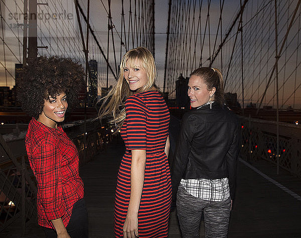 Frauen schauen beim Gehen auf der Brooklyn Bridge über die Schulter