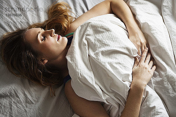 Draufsicht einer Frau  die zu Hause auf dem Bett schläft