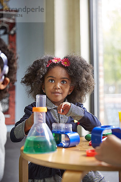 Überraschtes Mädchen schaut während eines wissenschaftlichen Experiments in der Vorschule weg