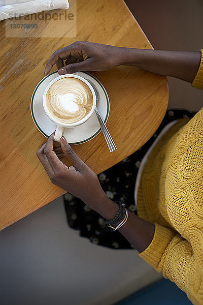Draufsicht einer Frau mit Cappuccino im Cafe sitzend