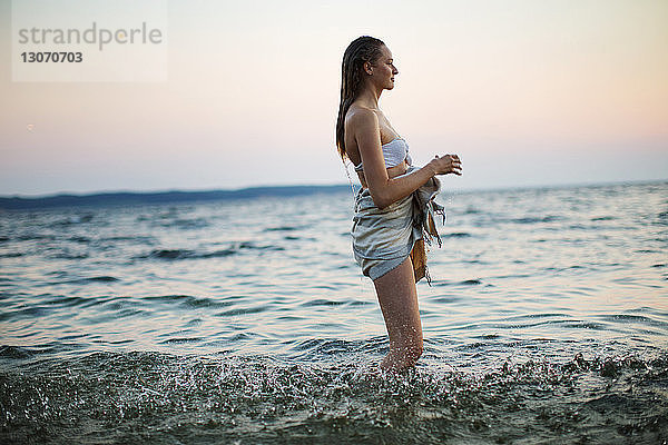 Seitenansicht einer Frau  die wegschaut  während sie im Meer steht