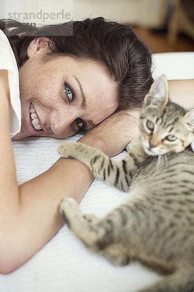 Porträt einer Frau mit Katze  die sich zu Hause auf dem Bett ausruht