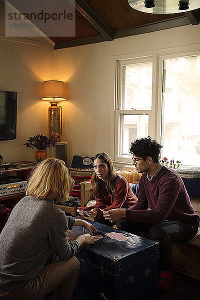 Freunde spielen mit Karten  während sie zu Hause im Wohnzimmer sitzen