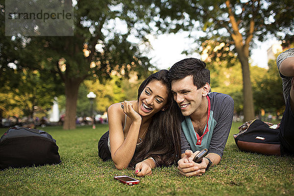 Glückliches Paar liegt auf einem Grasfeld auf dem Campus