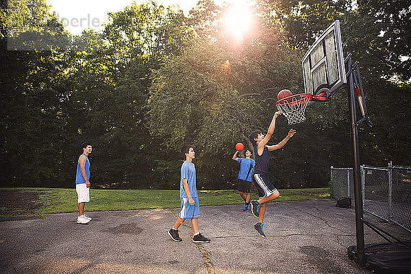 Spieler  die an sonnigen Tagen Basketball auf dem Platz gegen Bäume spielen