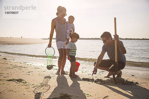 Familie sucht am Strand am Meeresufer vor klarem Himmel