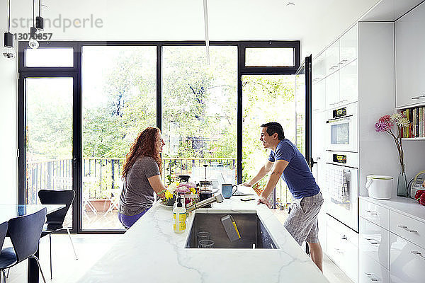 Glückliches Paar unterhält sich am Küchentisch am Fenster