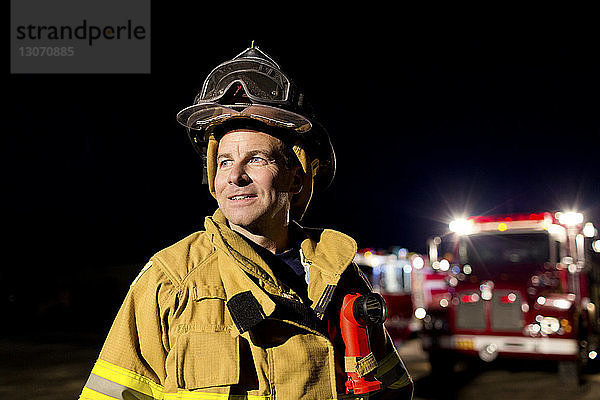 Feuerwehrmann schaut weg  während er nachts gegen den Himmel steht