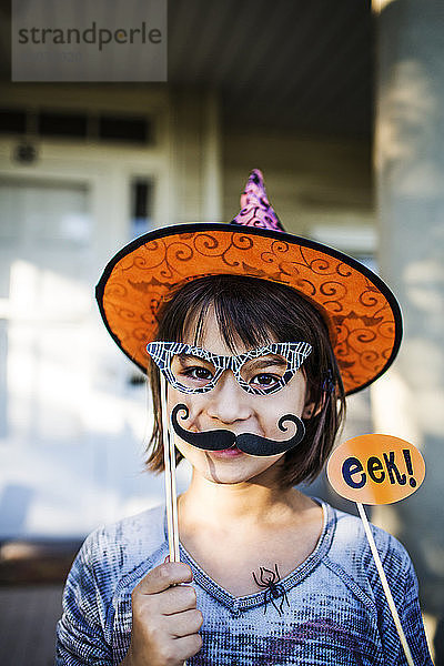 Porträt eines lächelnden Mädchens mit Requisiten während der Halloween-Party