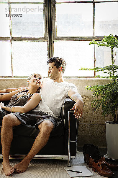 Glückliches Paar ruht sich zu Hause auf dem Sofa am Fenster aus