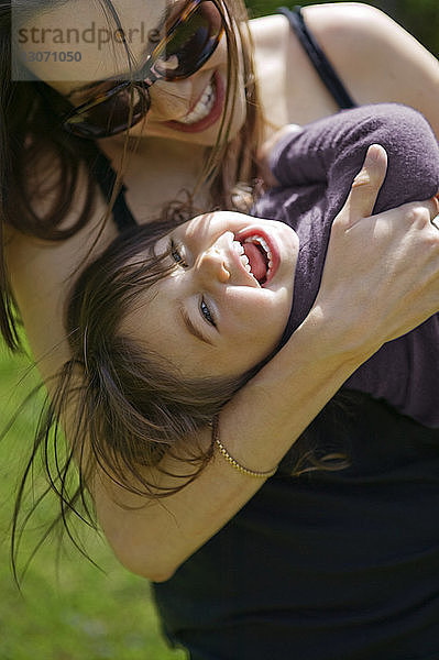Fröhliche Mutter und Tochter umarmen sich im Park