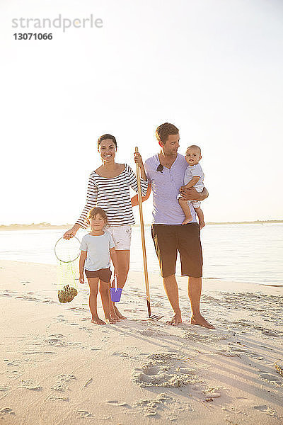 Glückliche Familie in voller Länge am Strand vor klarem Himmel stehend