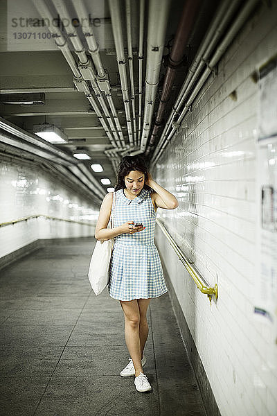 Frau in voller Länge beim Telefonieren während des Gehens in der U-Bahn