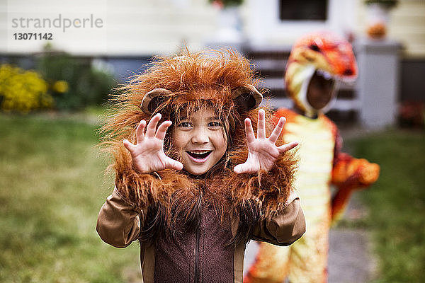 Porträt eines Mädchens in Halloween-Kostüm  das sich im Hof mit einem Freund im Hintergrund vergnügt