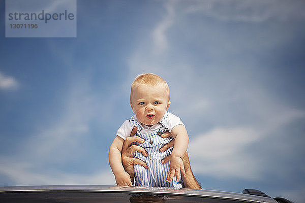 Porträt eines vom Vater gegen den Himmel getragenen Jungen