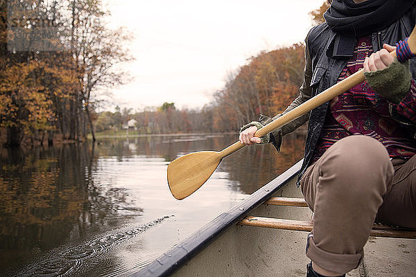 Mitschnitt eines Ruderbootes einer Frau auf einem See im Wald während des Winters