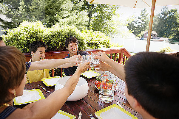Hochwinkelansicht einer Familie  die während des Essens auf der Veranda auf Trinkgläser anstößt