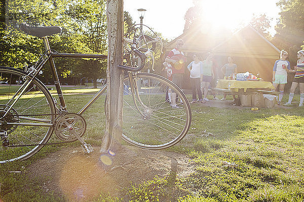 Fahrrad am Pfahl auf Grasfeld geparkt  während Freunde im Hintergrund stehen