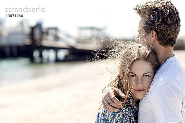 Mann umarmt Freundin am Strand
