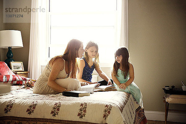 Mutter studiert Töchter  während sie zu Hause im Bett sitzt