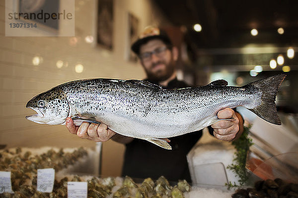 Mann zeigt Fisch  während er im Restaurant steht