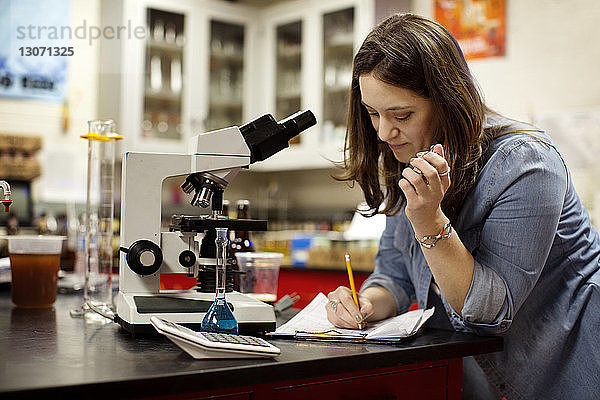 Frau arbeitet mit dem Mikroskop am Tisch in einer Brauerei