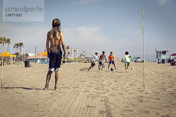 Kinder spielen Fussball am Strand gegen den Himmel