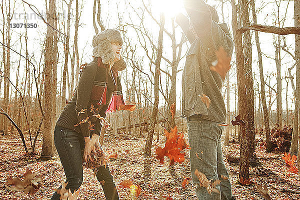 Paar spielt im Wald stehend mit Blättern