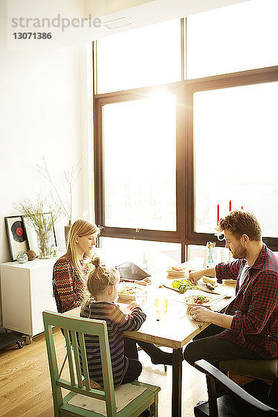 Glückliche Familie frühstückt zu Hause am Esstisch