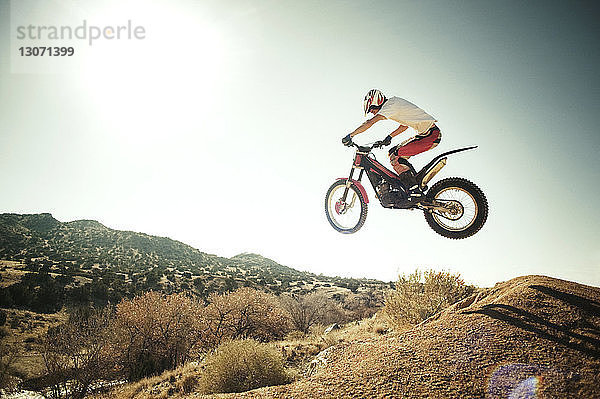 Seitenansicht eines Mannes  der vor klarem Himmel einen Stunt mit einem Motorrad macht