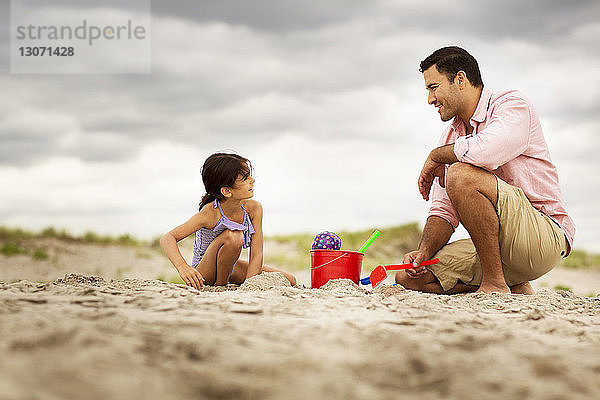Oberflächenniveau eines Vaters  der mit seiner Tochter am Strand spielt
