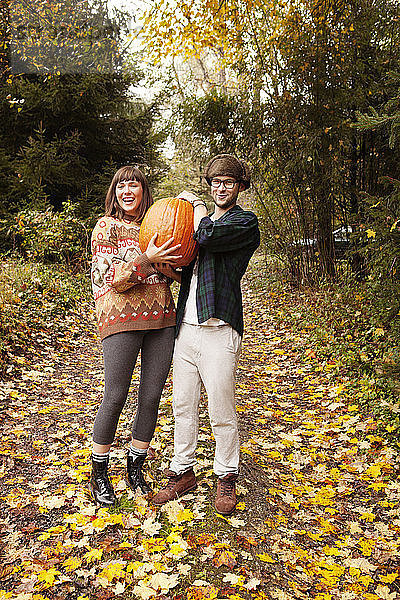 Porträt eines auf dem Feld stehenden Paares  das einen Halloween-Kürbis trägt