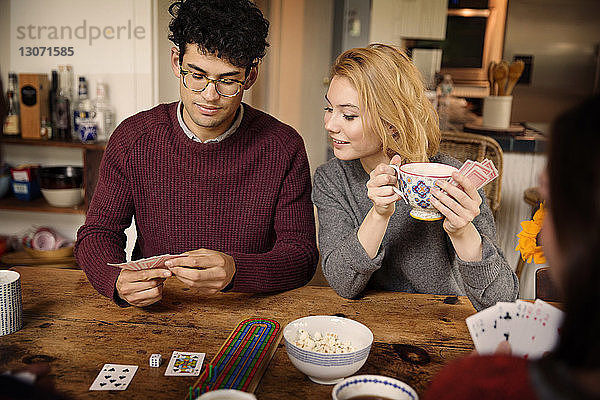 Freunde spielen Karten  während sie zu Hause Kaffee trinken