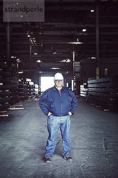 Porträt eines selbstbewussten Arbeiters mit Händen auf der Hüfte in der Fabrik