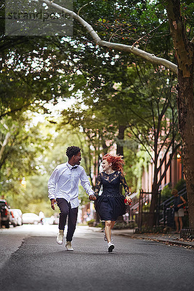Glückliches Paar hält Händchen und läuft auf der Straße