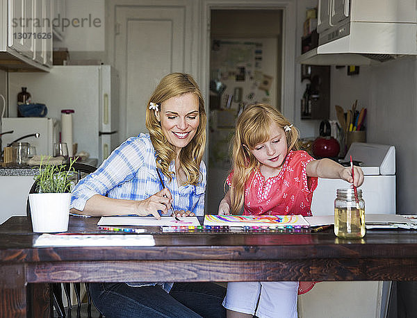 Mutter und Tochter malen zu Hause auf Buch