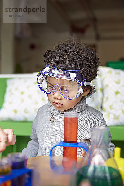 Süßer Junge mit Schutzbrille sucht nach Lösungen in der Vorschule