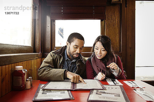 Ehepaar betrachtet die Speisekarte  während es im Restaurant sitzt