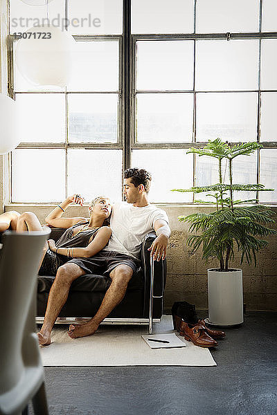 Paar redet  während es sich zu Hause auf dem Sofa am Fenster ausruht