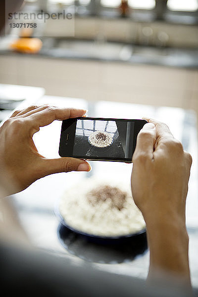 Frau fotografiert hausgemachte Torte mit Smartphone