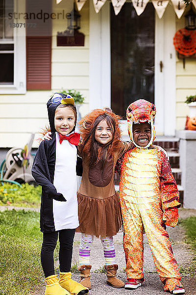 Porträt von glücklichen Freunden in Halloween-Kostüm  die vor dem Haus stehen
